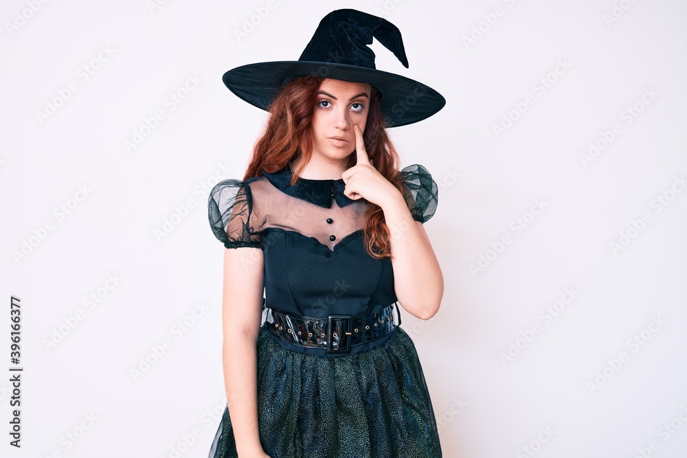 Young beautiful woman wearing witch halloween costume pointing to the eye watching you gesture, suspicious expression Young beautiful woman wearing witch halloween costume pointing to the eye watching you gesture, suspicious expression