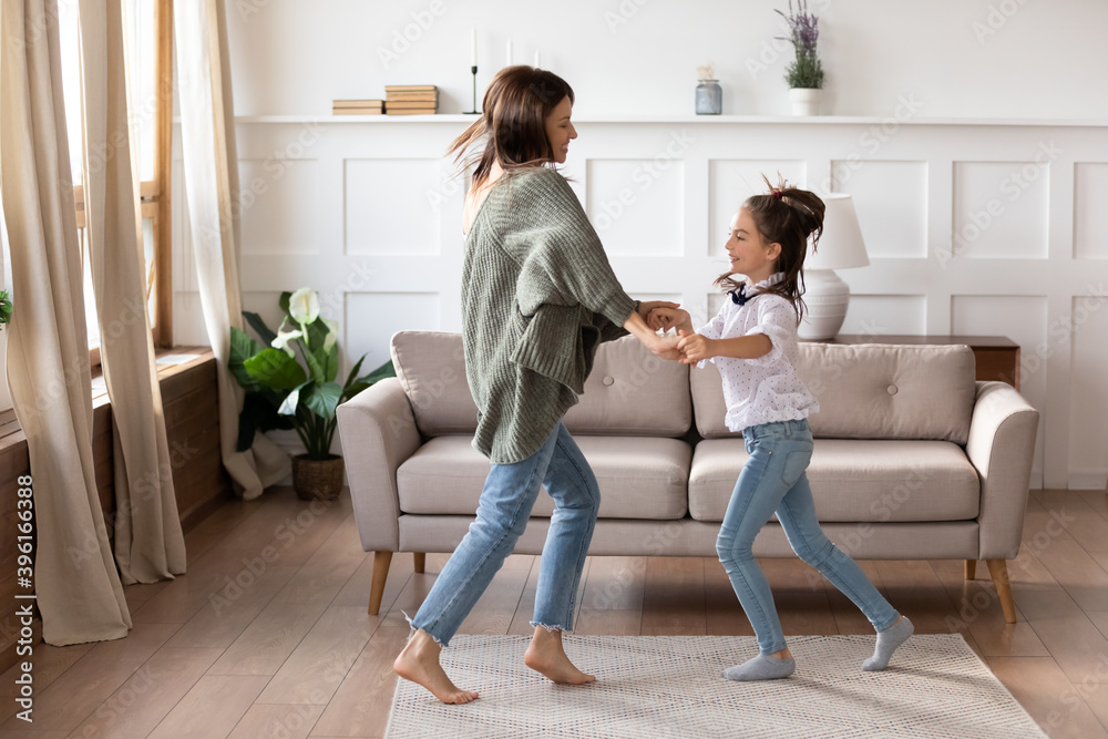 Φωτογραφία Happy young single mother dance with little schoolgirl daughter in cozy living room