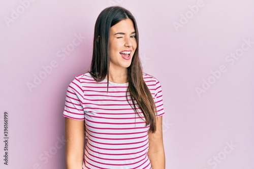 Young brunette woman wearing casual clothes over pink background winking looking at the camera with sexy expression, cheerful and happy face.
