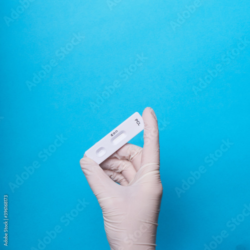 COVID-19 test to detect IgM and IgG antibodies to Novel Coronavirus, SARS-CoV-2 with positive result.Coronavirus Express Testing card. Covid-19 rapid test, on blue background. hand.gloves. copy space