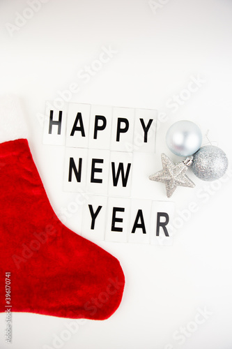 Santa's red stocking on a white background together with a toy in the form of a star and a ball. Happy new year lettering.