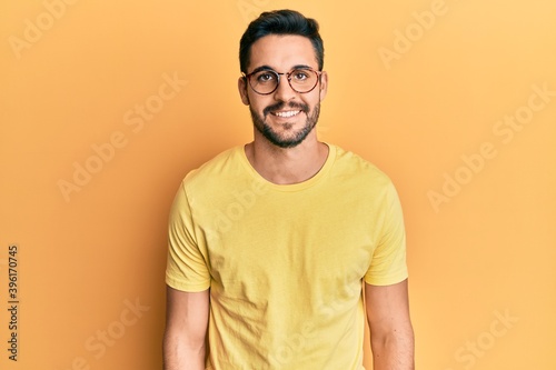 Young hispanic man wearing casual clothes and glasses with a happy and cool smile on face. lucky person. © Krakenimages.com