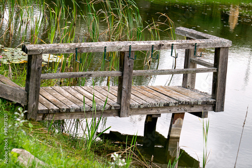 A small wooden pier made of planks for fishing by the lake.