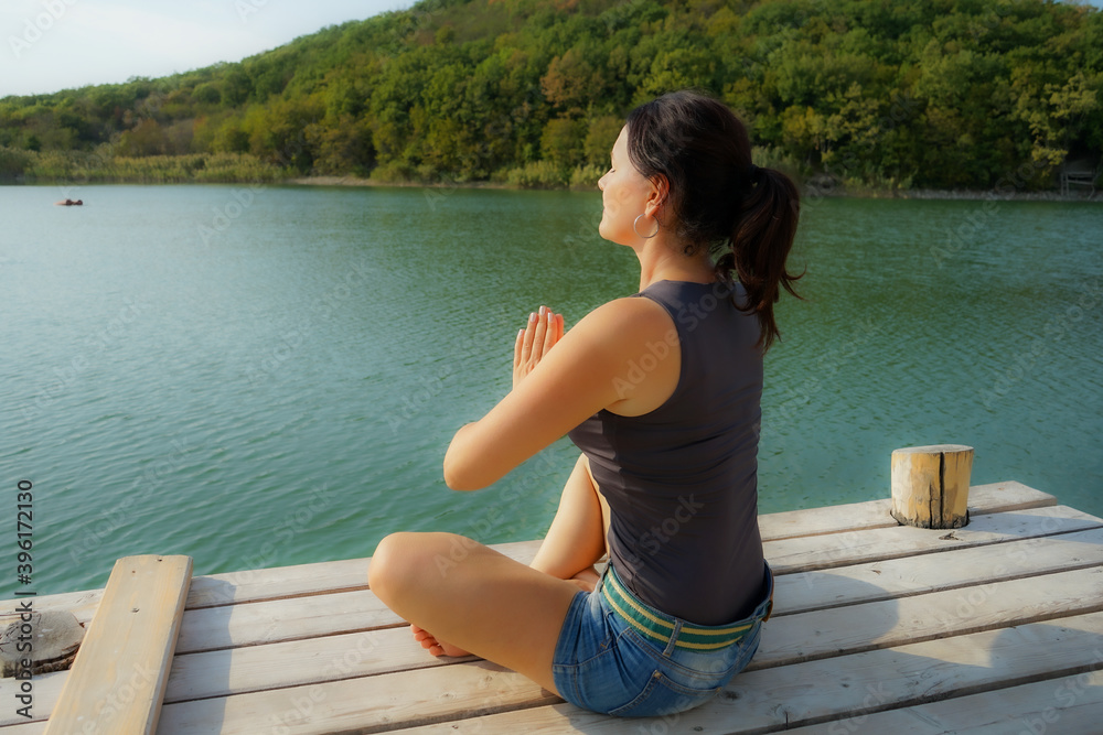 a woman is engaged in outdoor relaxation on a pier by the lake