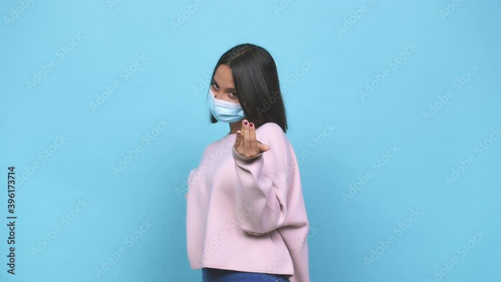Young hispanic woman wearing antiviral mask blink at the camera through fingers, embarrassed covering face Young hispanic woman wearing antiviral mask blink at the camera through fingers, embarrassed covering face