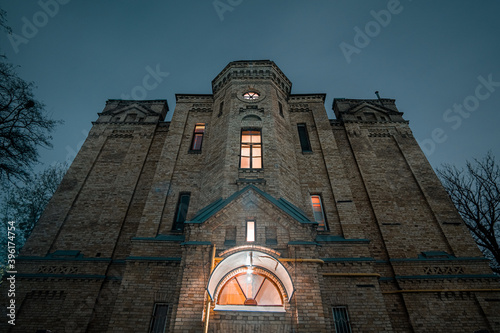 Bottom-up view of the sinister 19th-century brick house. at night with trees without leaves nearby. Old house on the territory of Kyiv Polytechnic Institute. photo