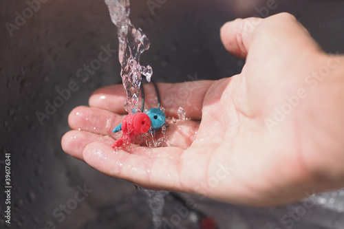 Slika na platnu Crop image. Hand washing earplugs in the sink.