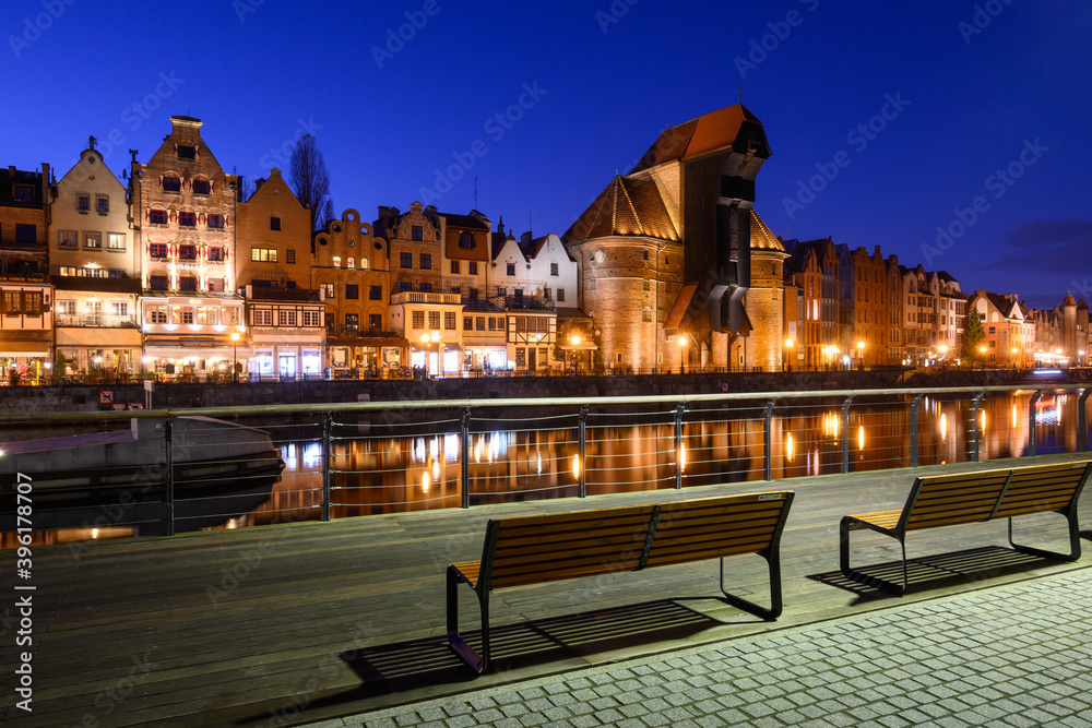 Promenade at Motlawa River with famous historic port crane at night. Poland, Europe.
