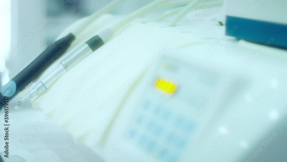 Dentist wearing glove picks modern dental drill, close-up shot Dentist wearing glove picks modern dental drill, close-up shot