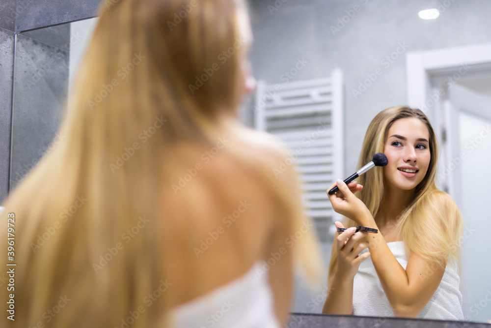 Body care series. Young woman applying powder with make up brush in bathroom Body care series. Young woman applying powder with make up brush in bathroom