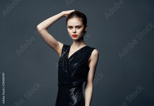 Charming lady in a black dress with bare shoulders on a gray background Copy Space