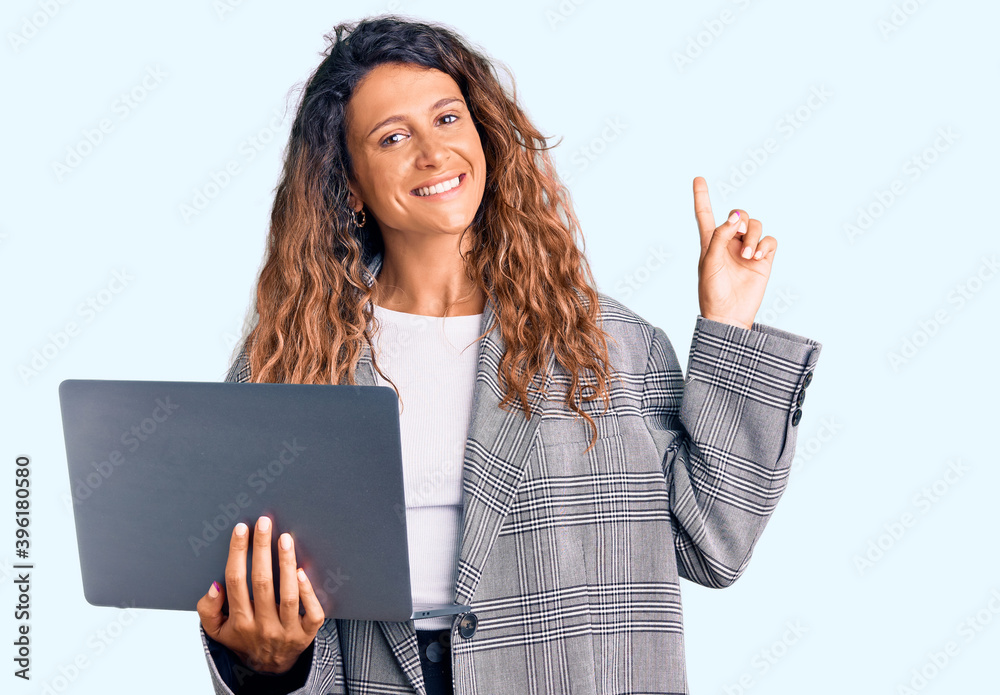 Young hispanic woman with tattoo holding laptop surprised with an idea or question pointing finger with happy face, number one Young hispanic woman with tattoo holding laptop surprised with an idea or question pointing finger with happy face, number one
