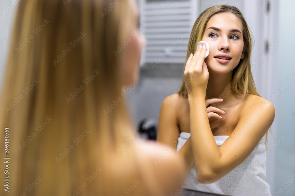 Young pretty woman is removing makeup with a cotton pad Young pretty woman is removing makeup with a cotton pad