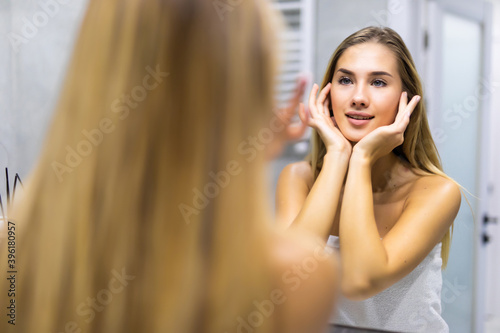 Young woman looking on reflection in the mirror after shower
