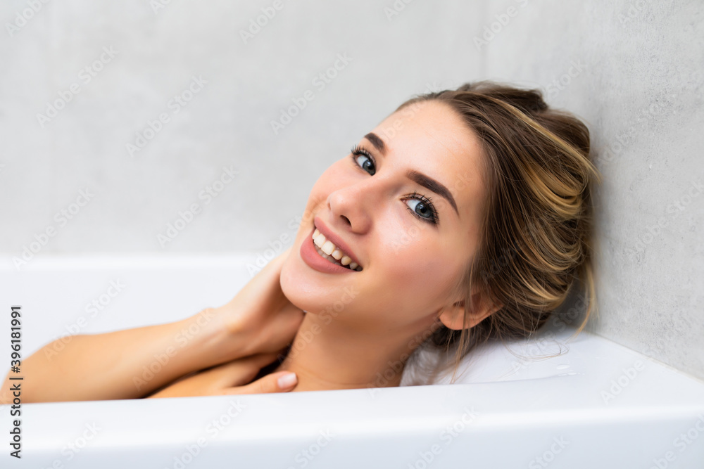 Beautiful young woman relaxing lying in the bathtube in the bathroom Beautiful young woman relaxing lying in the bathtube in the bathroom