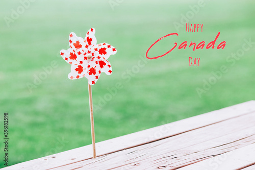 Canada Day text card background. Windmill whizzer with red maple leaves on white background outdoors. Toy with Canadian flag symbol. Canada Day national celebration on July 1. photo