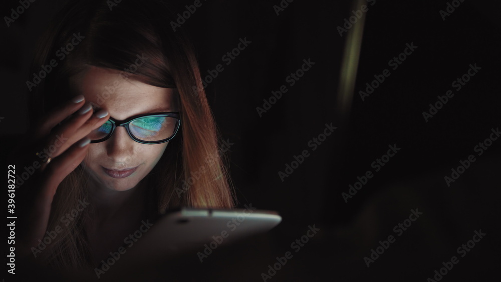 Close up of lonely young woman lying on sofa and using smartphone at night. Depressed millennial female staring at mobile phone screen and thinking. Concept of painful breakup Close up of lonely young woman lying on sofa and using smartphone at night. Depressed millennial female staring at mobile phone screen and thinking. Concept of painful breakup