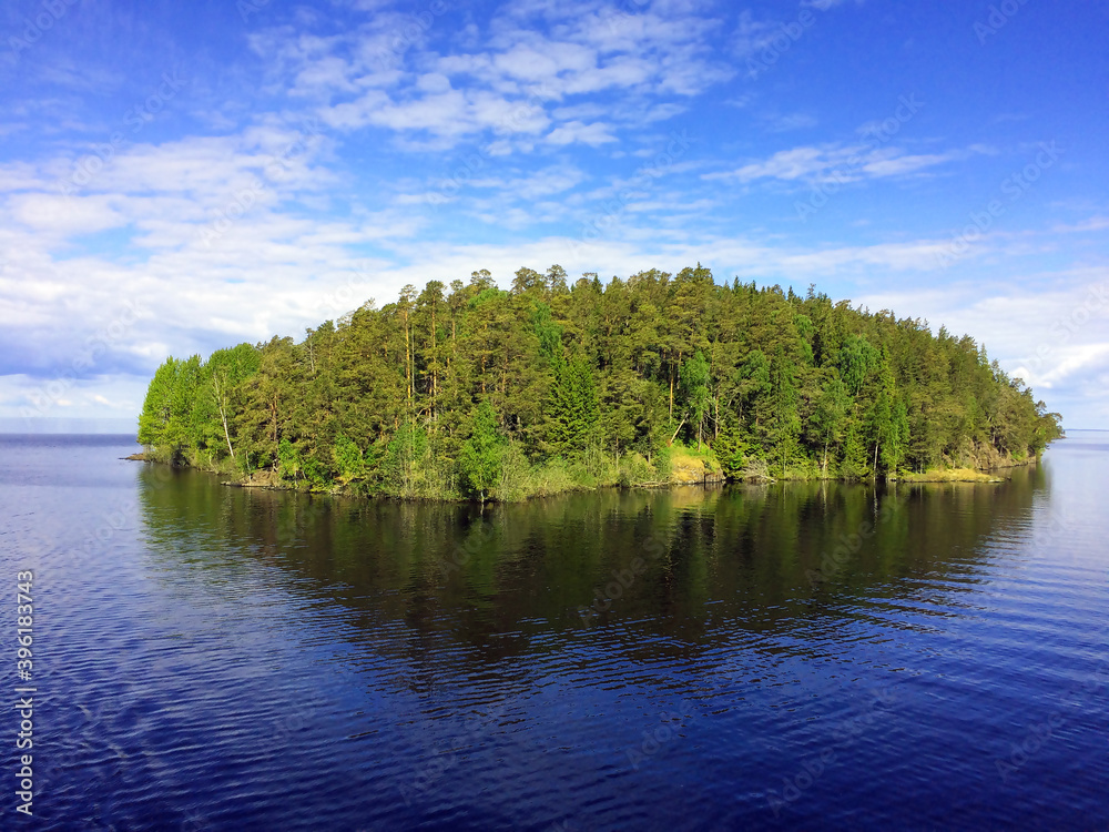 Skerry covered with green forest in the purest Lake of Ladoga. Morning in harmony with nature. Travel by cruise ship to Karelia, Valaam island.