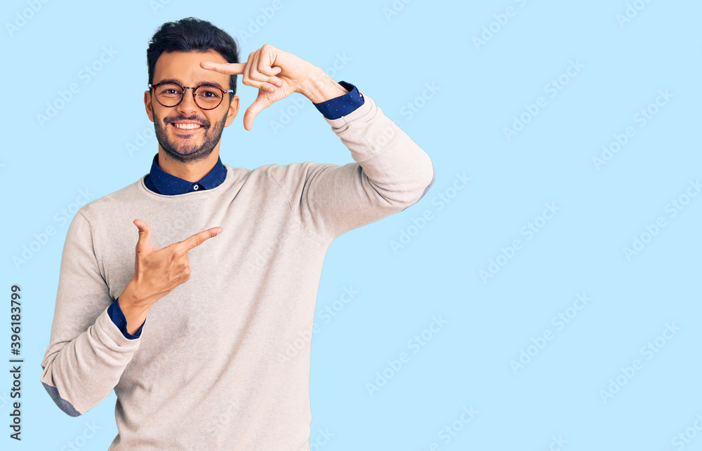 Young handsome hispanic man wearing elegant clothes and glasses smiling making frame with hands and fingers with happy face. creativity and photography concept. Young handsome hispanic man wearing elegant clothes and glasses smiling making frame with hands and fingers with happy face. creativity and photography concept.