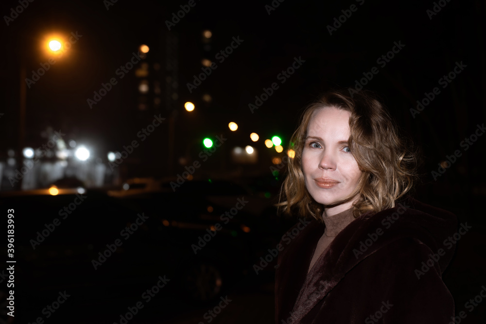 A woman stands near the road at night in the fall. A woman stands near the road at night in the fall.