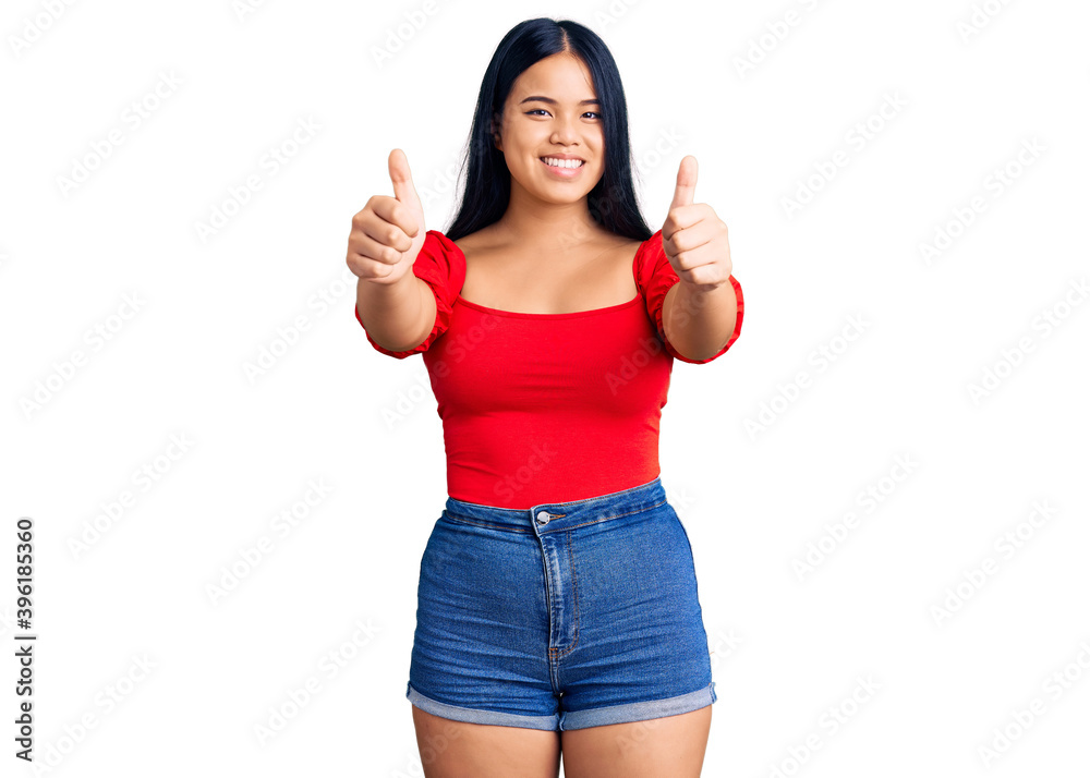 Young beautiful asian girl wearing casual clothes approving doing positive gesture with hand, thumbs up smiling and happy for success. winner gesture. Young beautiful asian girl wearing casual clothes approving doing positive gesture with hand, thumbs up smiling and happy for success. winner gesture.