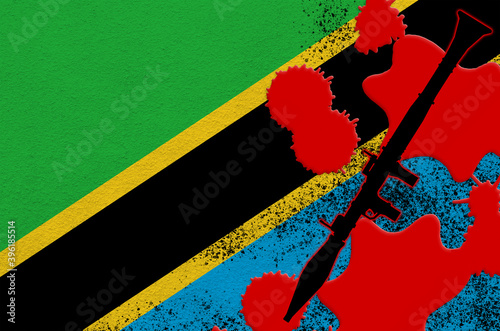 Tanzania flag and black RPG-7 rocket-propelled grenade launcher in red blood. Concept for terror attack or military operations with lethal outcome photo