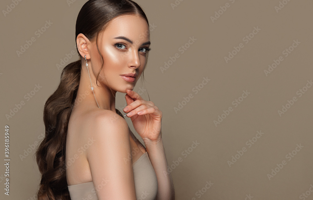 Beautiful girl with  curled tail on her  head . Fashionable and stylish woman in trendy jewelry big earrings rings  .  Fashion look  , beauty and style. Natural makeup & easy styling - obrazy, fototapety, plakaty 