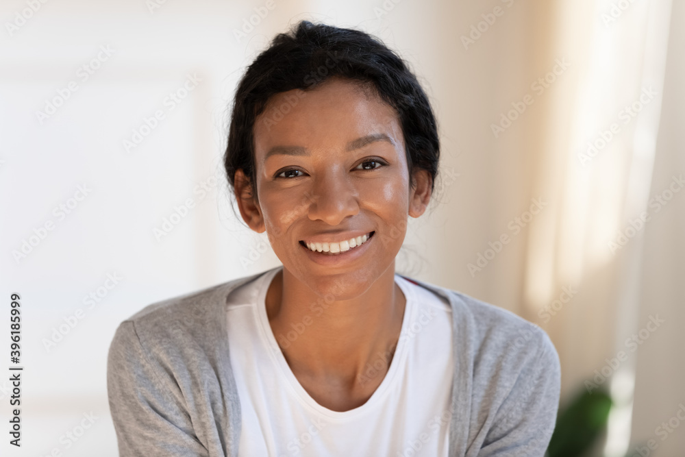 Close up headshot portrait of smiling young African American woman renter or tenant at home. Profile picture of happy millennial biracial 20s female have video call or webcam digital virtual talk. Close up headshot portrait of smiling young African American woman renter or tenant at home. Profile picture of happy millennial biracial 20s female have video call or webcam digital virtual talk.