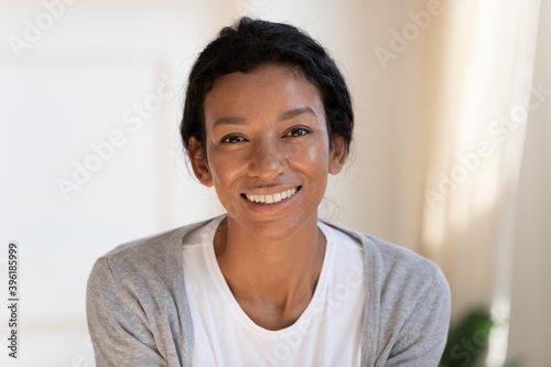 Close up headshot portrait of smiling young African American woman renter or tenant at home. Profile picture of happy millennial biracial 20s female have video call or webcam digital virtual talk.