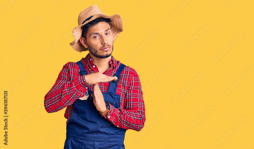 Handsome latin american young man weaing handyman uniform doing time out gesture with hands, frustrated and serious face Handsome latin american young man weaing handyman uniform doing time out gesture with hands, frustrated and serious face