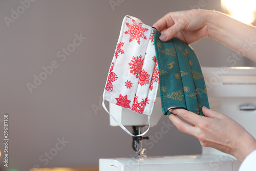 A close-up shot of female hands showing a set of Christmas designed disposable cotton face masks. Hobby and Christmas concept photo