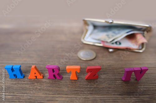 money, euro banknotes, black wallet, word in German Hartz IV made of colored letters lie on old wooden table, concept of social assistance to poor, unemployment benefit photo