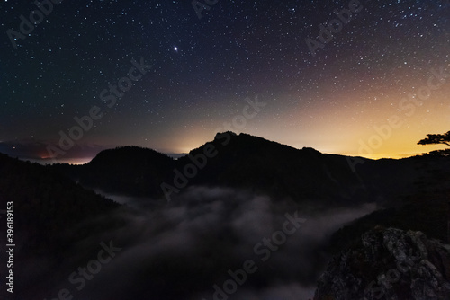 A beautiful starry night in the mountains on top with beautiful scenery and fog. 