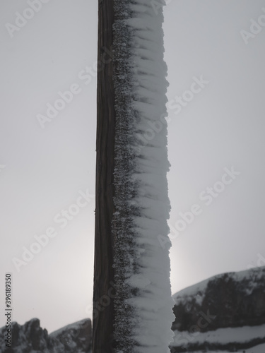 Foto closeup of snow on a wooden pole and snowy mountains in background