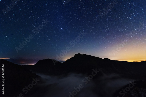 A beautiful starry night in the mountains on top with beautiful scenery and fog. 