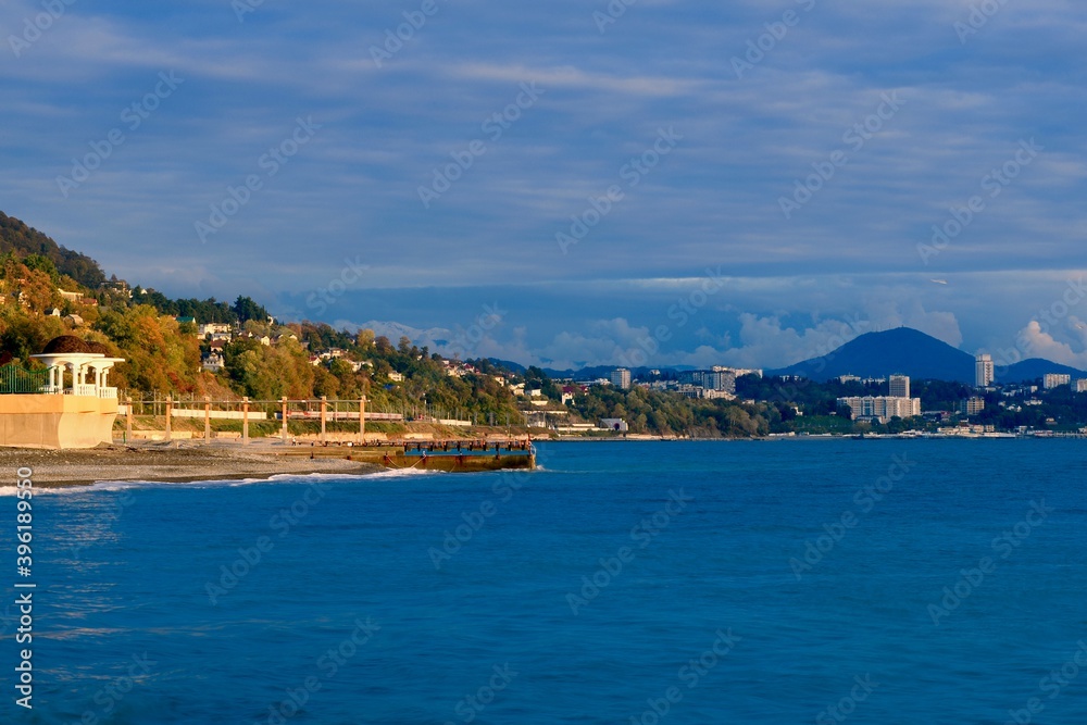 sea coast with a cape with a rotunda on a pebble beach against the backdrop of a mountain town