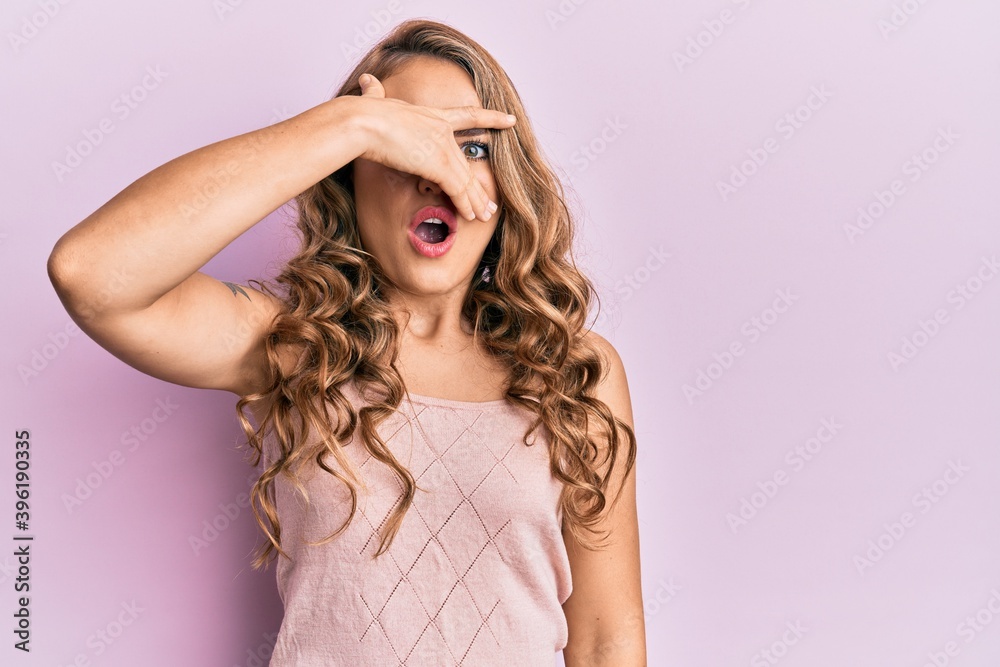 Young blonde girl wearing casual clothes peeking in shock covering face and eyes with hand, looking through fingers with embarrassed expression. Young blonde girl wearing casual clothes peeking in shock covering face and eyes with hand, looking through fingers with embarrassed expression.
