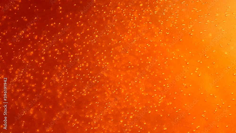 Close-up of effervescent orange bubbles from above. Close-up of effervescent orange bubbles from above.