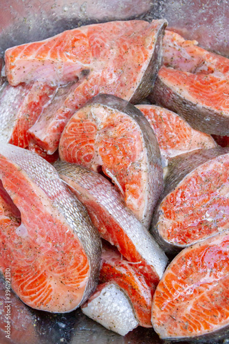 Fresh trout steaks are marinated in a metal bowl before cooking