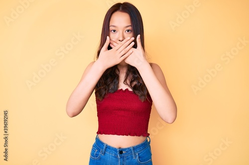 Young beautiful chinese girl wearing summer clothes shocked covering mouth with hands for mistake. secret concept.