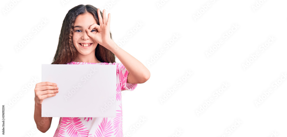 Cute hispanic child girl holding blank empty banner smiling happy doing ok sign with hand on eye looking through fingers Cute hispanic child girl holding blank empty banner smiling happy doing ok sign with hand on eye looking through fingers