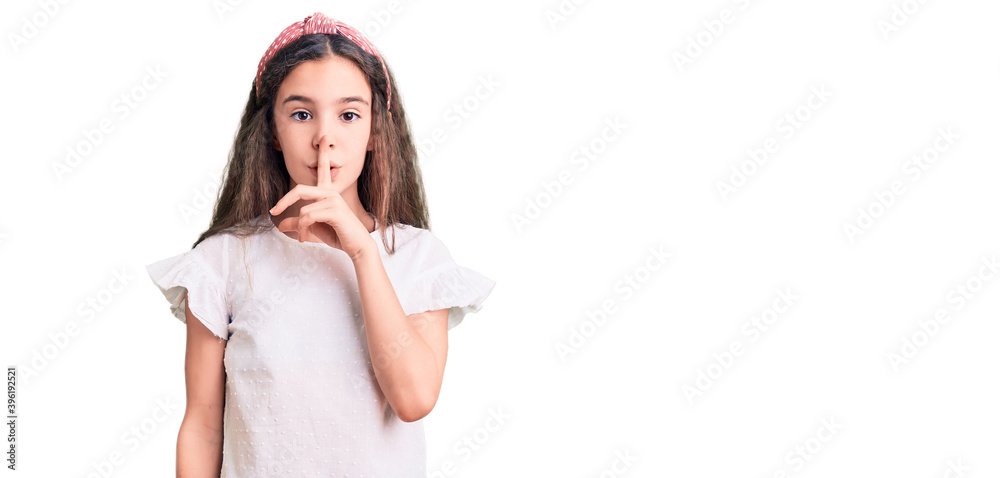 Cute hispanic child girl wearing casual white tshirt asking to be quiet with finger on lips. silence and secret concept. Cute hispanic child girl wearing casual white tshirt asking to be quiet with finger on lips. silence and secret concept.