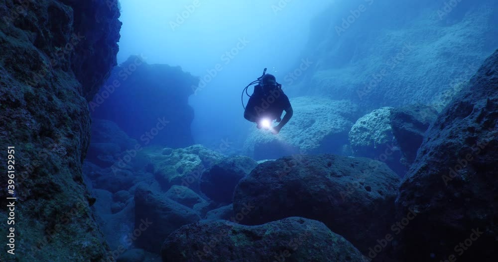 scuba divers exploring the reefs and underwater with rocks ocean scenery