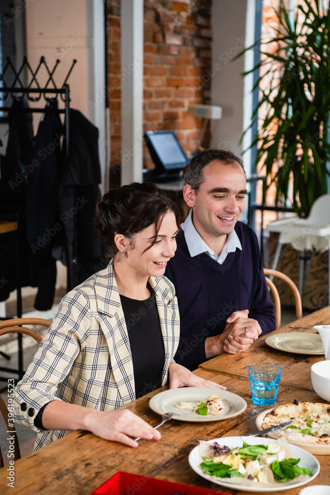 Young happy beautiful smiling couple enjoying dinner together by served restaurant table. Young happy beautiful smiling couple enjoying dinner together by served restaurant table.