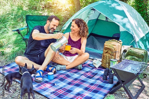 Middle age couple  of hiker smiling happy drinking coffee camping at the forest.