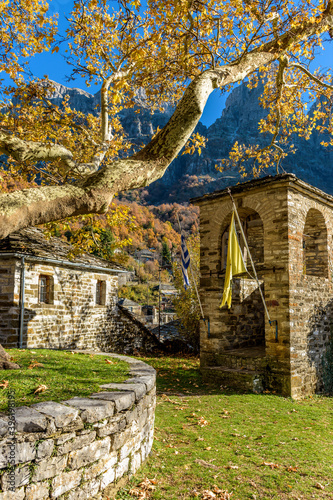 Taxiarchon stone bell tower   church  during  fall season in the picturesque village of Mikro  papigo in Epirus zagori greece photo