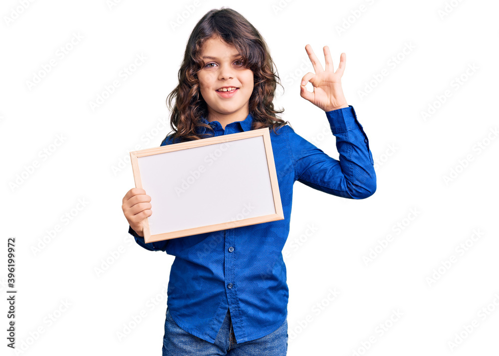 Cute hispanic child with long hair holding empty white chalkboard doing ok sign with fingers, smiling friendly gesturing excellent symbol Cute hispanic child with long hair holding empty white chalkboard doing ok sign with fingers, smiling friendly gesturing excellent symbol