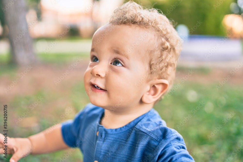 Cute and happy little boy having fun at the park on a sunny day. Beautiful blonde hair male toddler playing outdoors Cute and happy little boy having fun at the park on a sunny day. Beautiful blonde hair male toddler playing outdoors