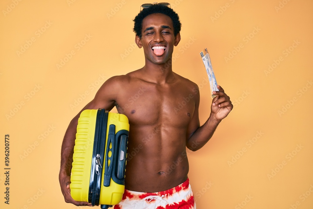 African handsome man going on summer trip holding boarding pass sticking tongue out happy with funny expression. African handsome man going on summer trip holding boarding pass sticking tongue out happy with funny expression.