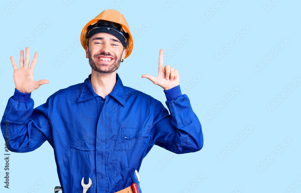 Young hispanic man wearing worker uniform showing and pointing up with fingers number seven while smiling confident and happy. Young hispanic man wearing worker uniform showing and pointing up with fingers number seven while smiling confident and happy.